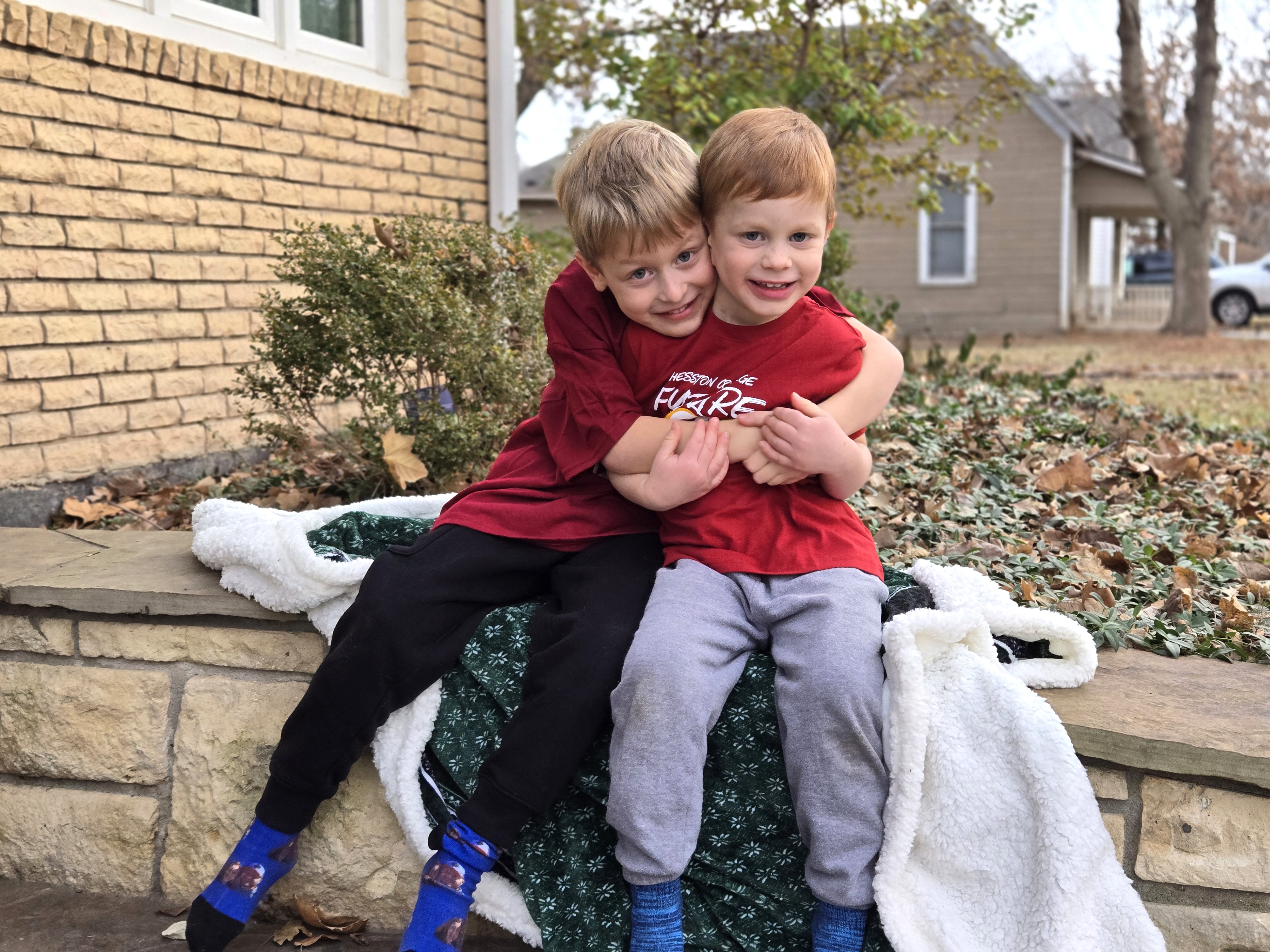 photo of two boys in maroon T-shirts with text, 