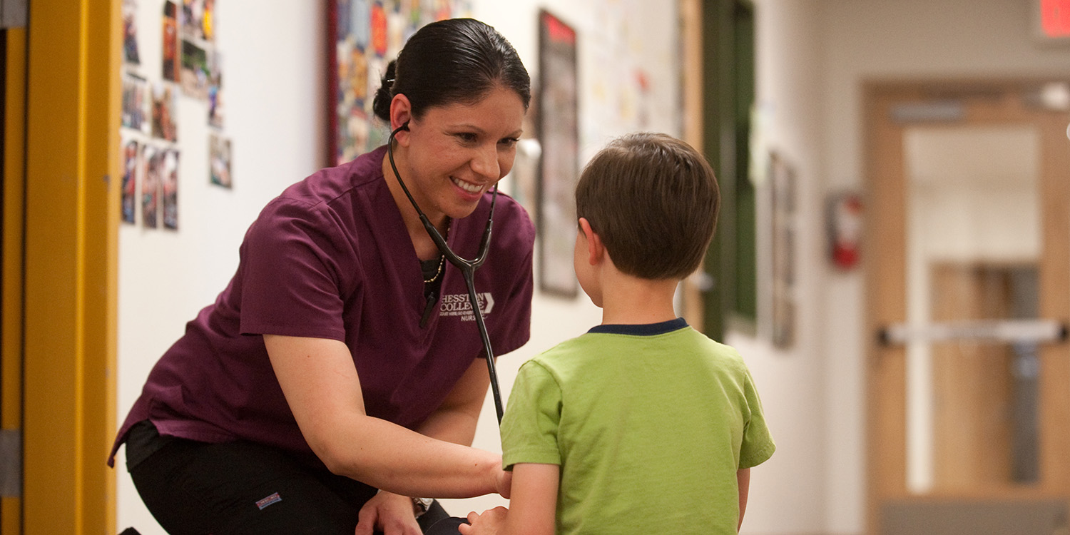 photo - 2016 Hesston College Nursing graduate Dra Aguilar (Wichita, Kan.) practices nursing skills on a young patient in this 2015 photo.