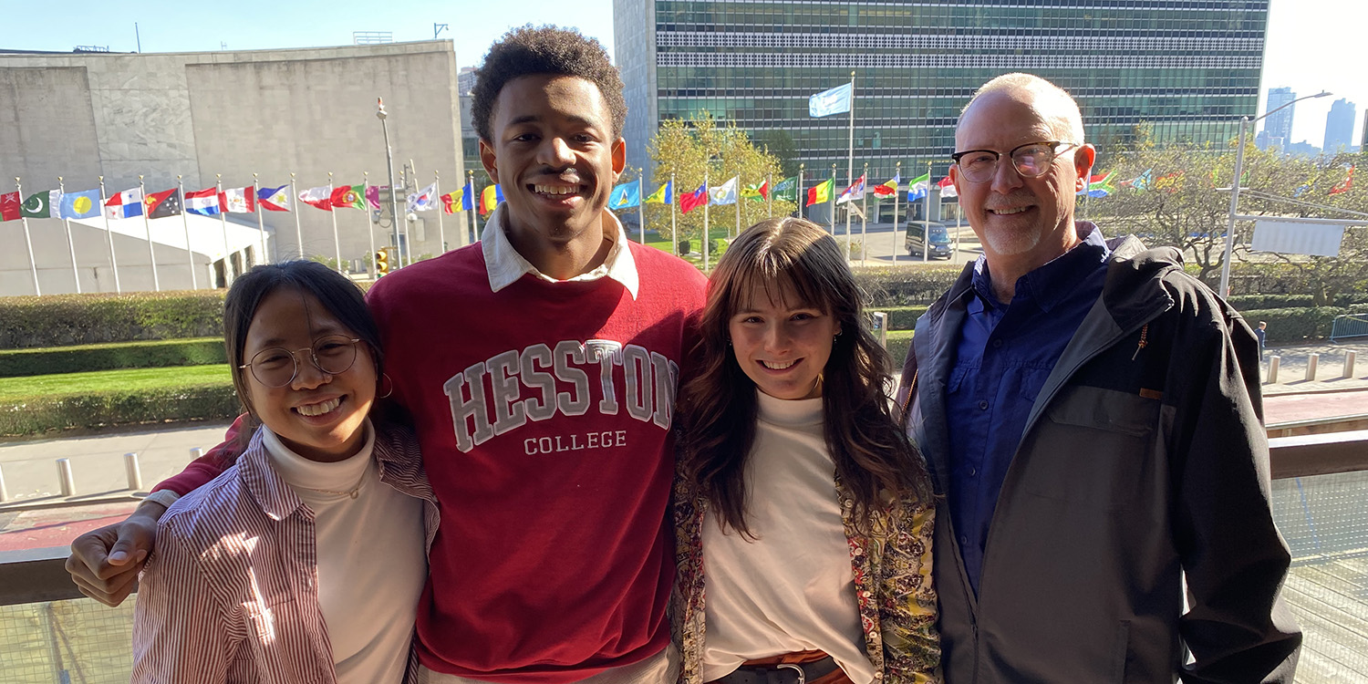 Three students and a professor pose at the UN building.