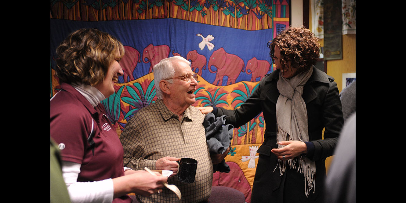 photo - Bill Mason (center), longtime Hesston College employee, is congratulated by Melissa Unruh (left) and Rachel Swartzendruber Miller (right) during Mason’s retirement celebration at Hesston College Feb. 16.