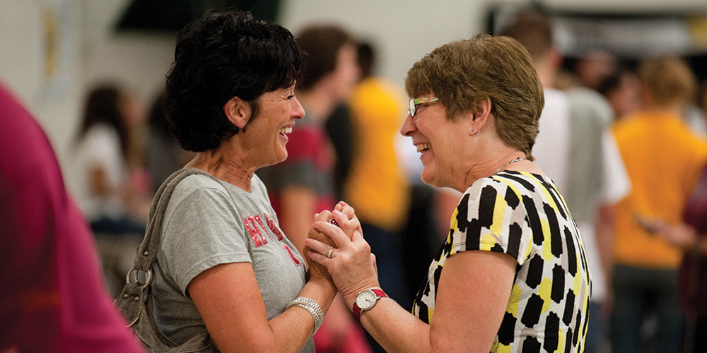 photo - Sue (Eicher) ’73 Roth and Priscilla (Wyse) ’72 Clemens greet each other at the tailgate barbecue picnic and family festival Friday.