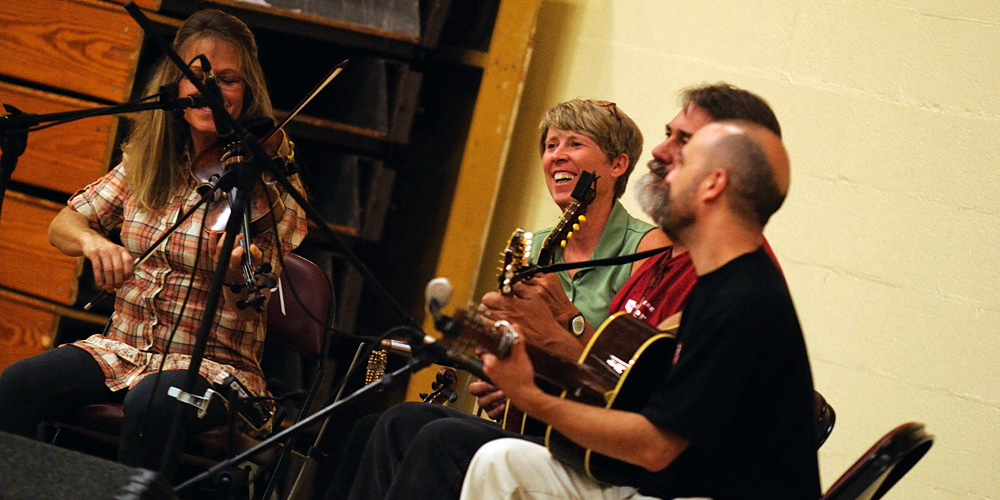 photo - Gretchen Priest May, Dave Firestine and Tim May play live bluegrass music for the contra dance. Faculty member Jen LeFevre (second from left) was the caller for the evening.