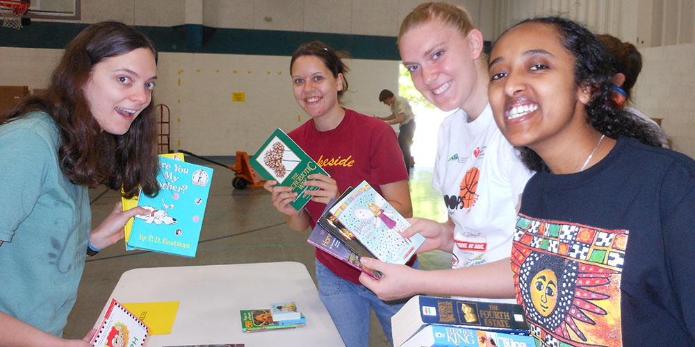 photo - Hesston college students (from left) Evette Yoder (Phoenix, Ariz.), Anna Yoder (Garden City, Mo.), Carly Unruh (Wayland, Iowa) and Asbel Assefa (Addis Ababa, Ethiopia) package books for Ethiopia Reads during the campus packaging event sponsored by the African Student Union. Photo by Kendra Litwiller.