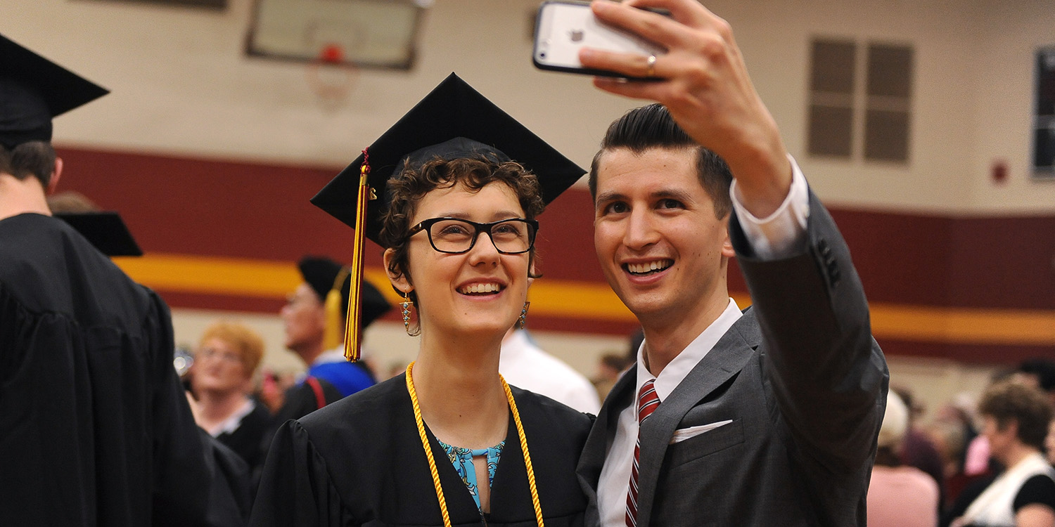 photo - Graduate RaeLee Hightower (Tulsa, Okla.) takes a post-graduation selfie with English faculty member Donovan Tann.