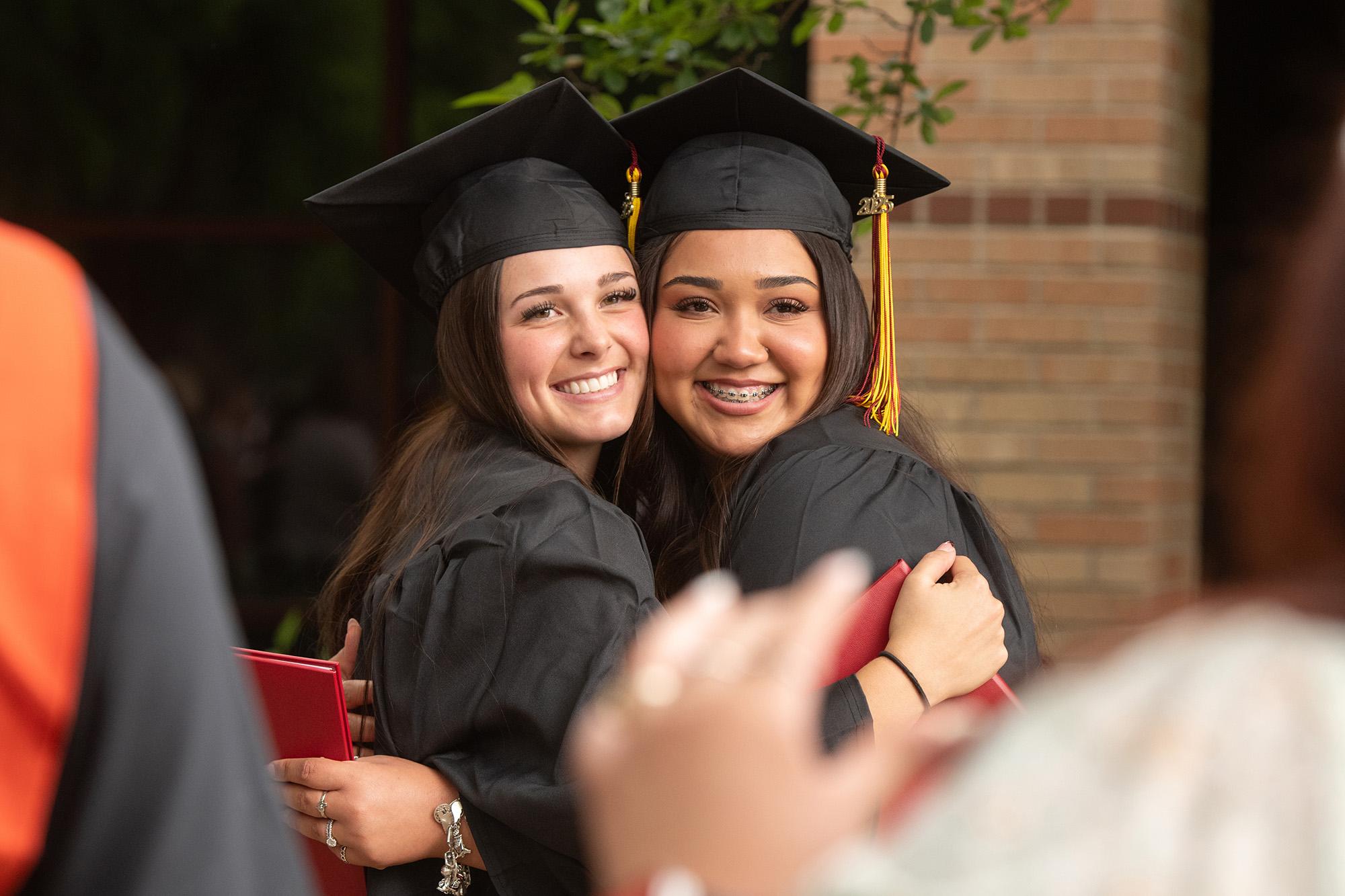 graduates embrace and pose for a photo after commencement