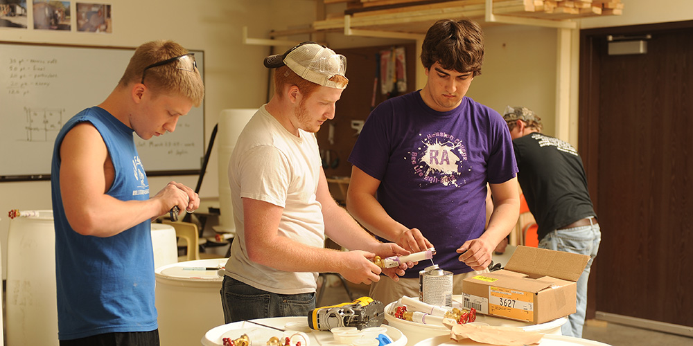 photo - Entrepreneurship students Hayden Goerzen (Newton, Kan.), Brandon Sharkey (Goshen, Ind.) and Kyle Albrecht (Clarence, N.Y.) assemble rain barrels for their business, Menno Barrel.