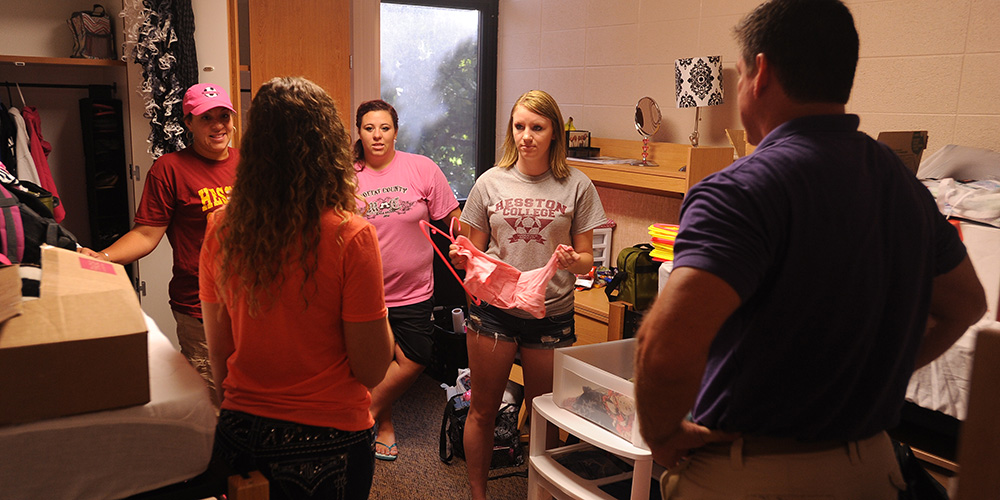 photo - Hesston College freshmen Skylar Tripp and Kambree Carter and their parents talk with their resident assistant, Hayley Goevert, Hesston, Kan., as they move into the dorms Aug. 12.