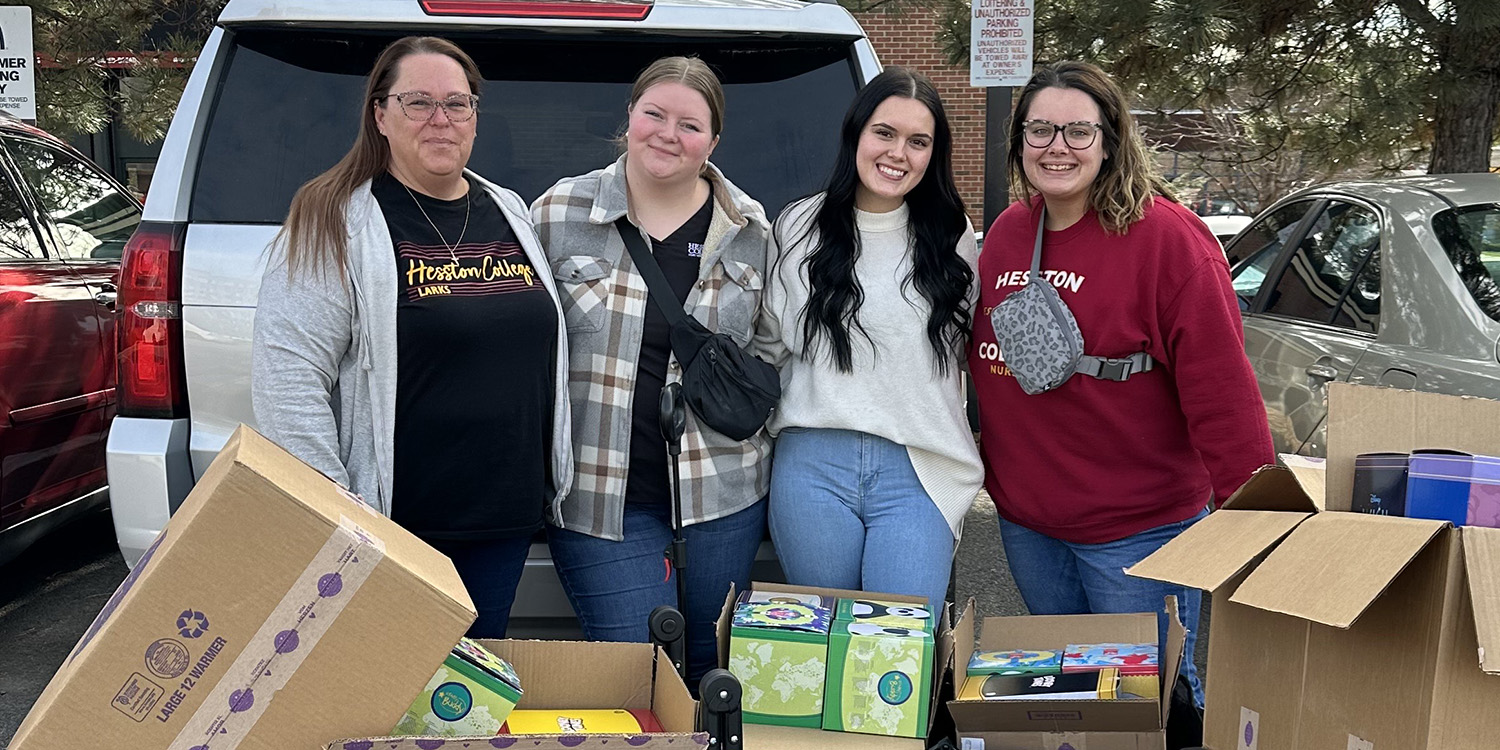 Four nursing students pose for photo with boxes of supplies.