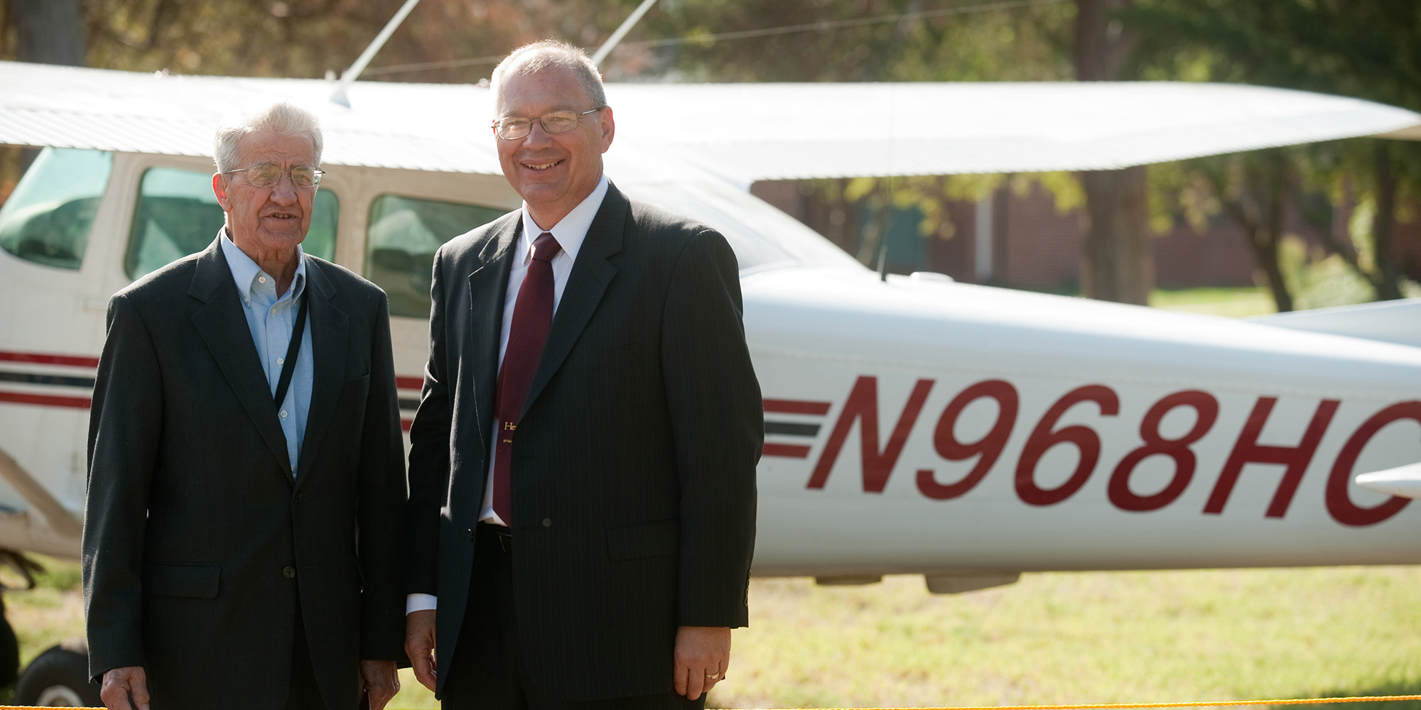 photo - Former President Laban Peachey (1968 to 1980) and President Howard Keim pose with the Hesston College airplane with the radio call numbers in honor of President Peachey.