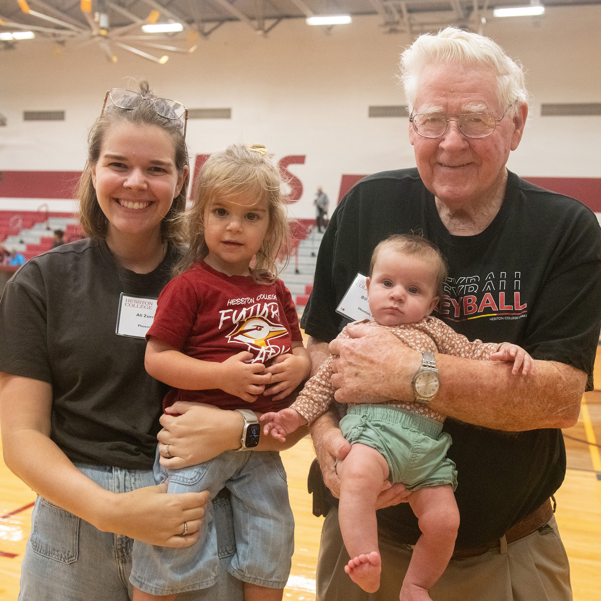 2026 homecoming photo - alumni Ali Zuercher and her grandfather, Bill, hold Ali's children - future Larks!