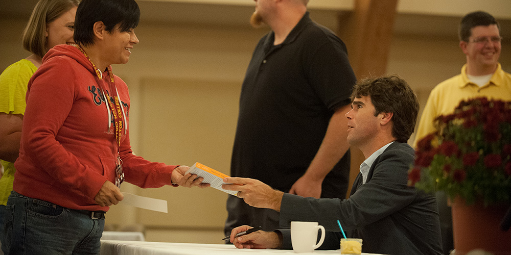 photo - Warren St. John autographs copies of his book, “Outcasts United,” at Hesston College Sept. 19.