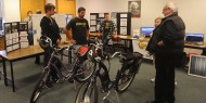 Hesston College physics students Keenan Jensen and Ron Wenger talk with Earth Day guests about the electric bicycles with solar power charging stations they helped build.