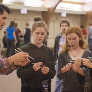 Hesston College sophomore Kaho Yanagidaira and English faculty member Donovan Tann give a lesson on using chopsticks to sophomores Morgan Leavy and Emily Griffioen at the college’s annual Culture’s Fair Oct. 10.