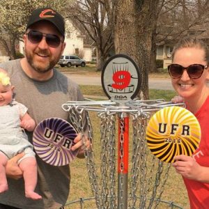 CJ (Unruh) Byler along with her husband, Billy, and daughter, Hazel, play a round of disc golf at Hesston College on the newly installed course in memory of her father, Doug.